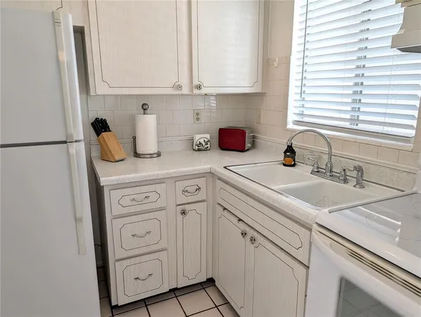 a kitchen with white cabinets and sink