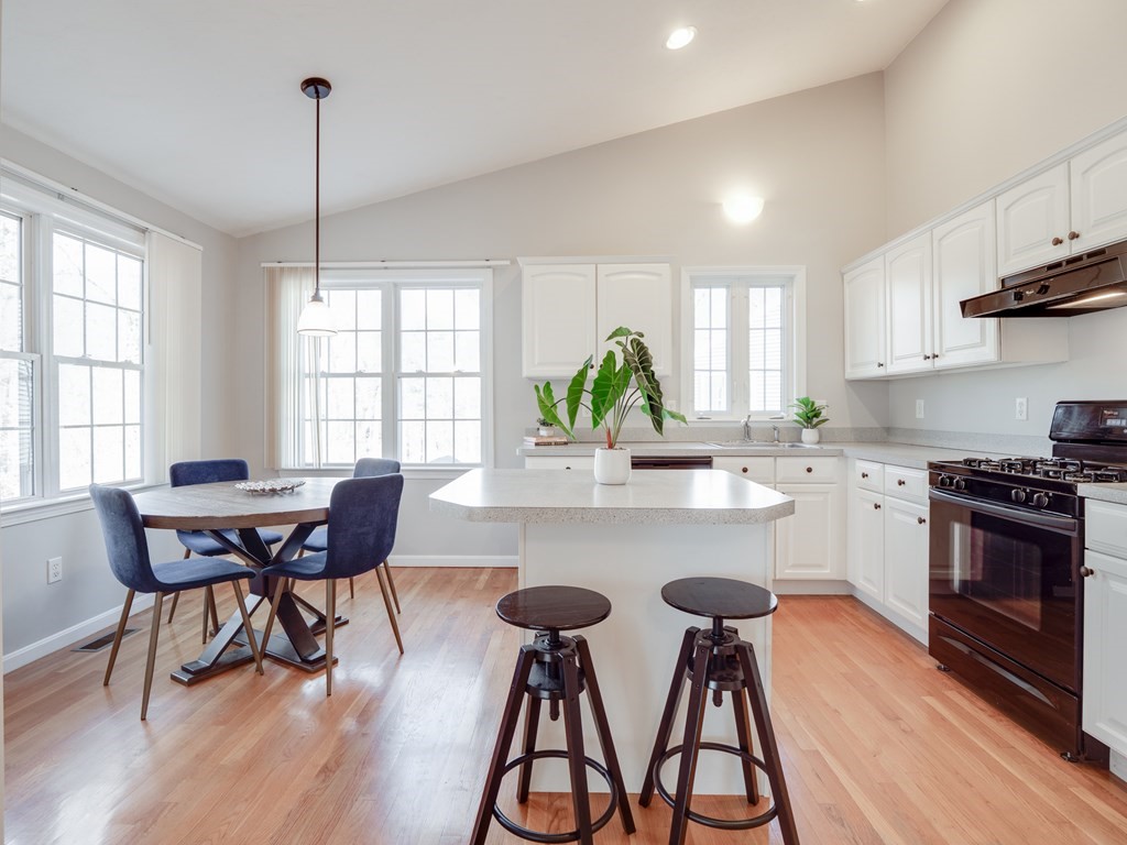 101 Stow Road, Unit 7 Boxborough, MA 01719 - Photo 14 of 32 a kitchen with stainless steel appliances a dining table chairs stove and white cabinets