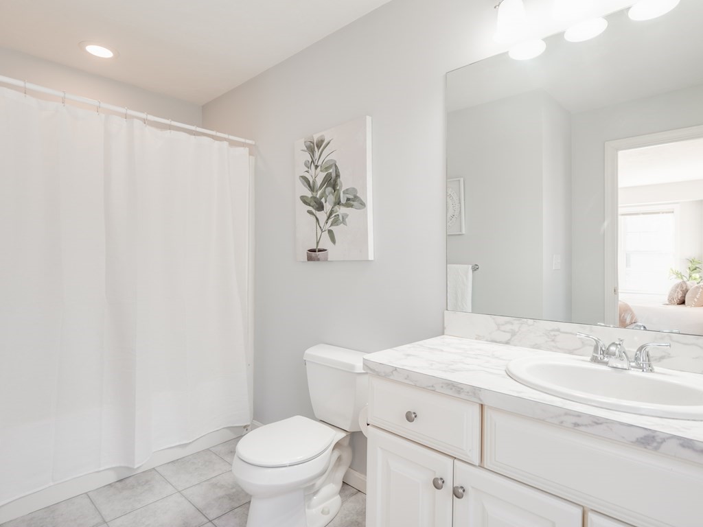 101 Stow Road, Unit 7 Boxborough, MA 01719 - Photo 23 of 32 a bathroom with a granite countertop sink a toilet and a mirror
