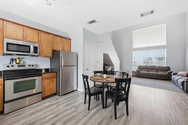 a kitchen with stainless steel appliances a stove a refrigerator a sink a dining table and chairs