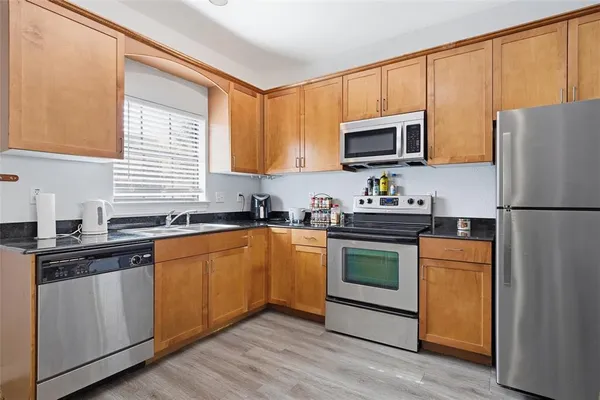 a kitchen with stainless steel appliances granite countertop a refrigerator stove a sink dishwasher and microwave with wooden floor