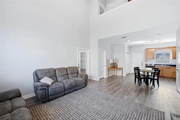 a living room with furniture and a dining table with wooden floor