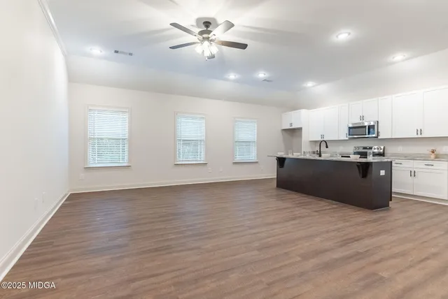 a large kitchen with hardwood floor a sink stainless steel appliances and cabinets
