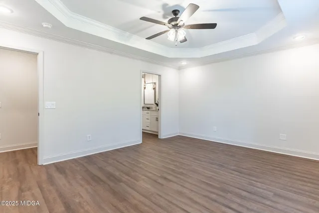 an empty room with wooden floor and ceiling fan