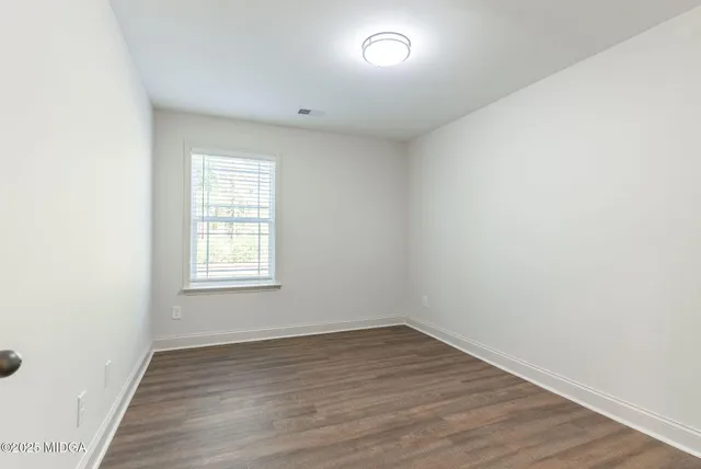 an empty room with wooden floor and window
