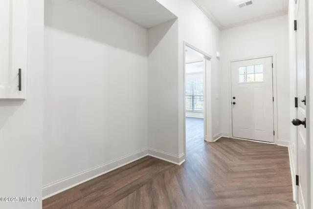 a view of an empty room with wooden floor and a window