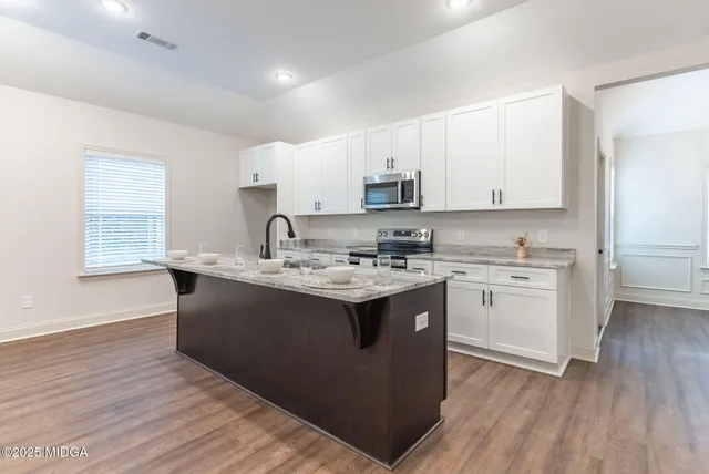 a kitchen with kitchen island granite countertop a sink appliances cabinets and a counter top space