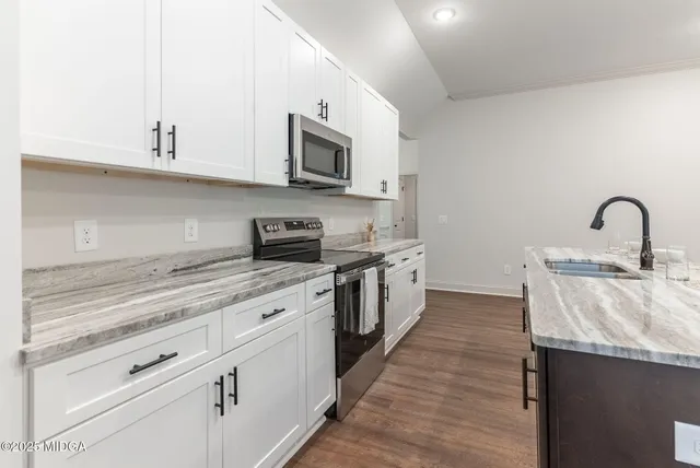 a kitchen with stainless steel appliances granite countertop a stove a sink and a microwave