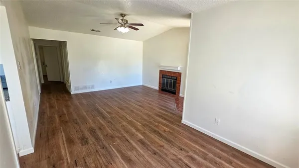 an empty room with wooden floor fan and windows