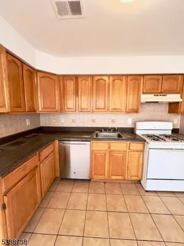 a kitchen with granite countertop a stove sink and cabinets