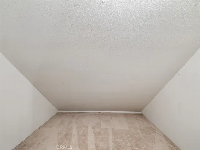 a view of an empty room with window and chandelier fan