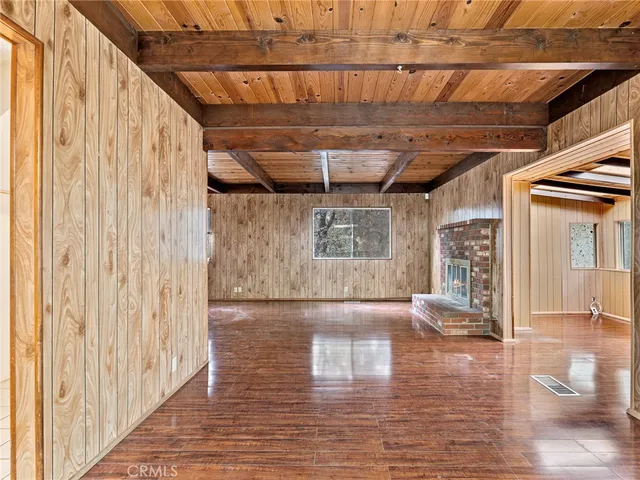 a view of an empty room with wooden floor and windows