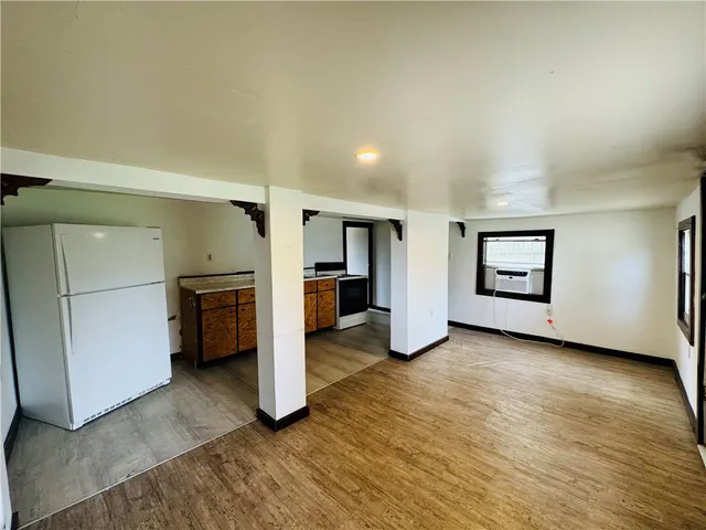 a view of a kitchen with refrigerator and an empty room