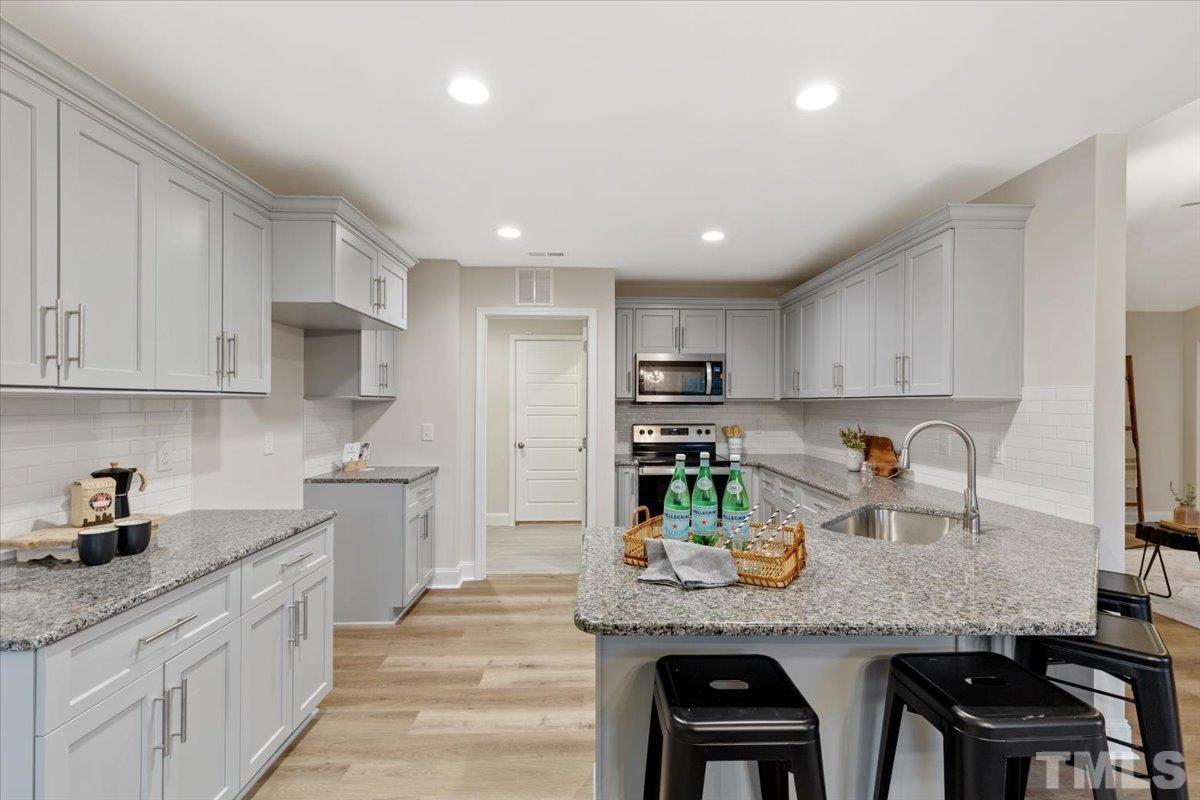 a large kitchen with granite countertop lots of counter space white cabinets and stainless steel appliances