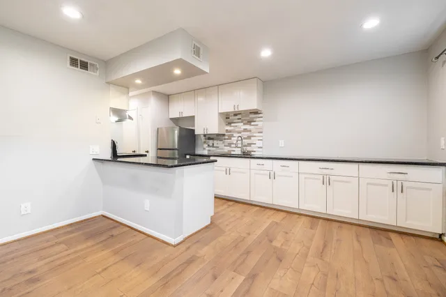 a kitchen with stainless steel appliances granite countertop a white cabinets and wooden floor