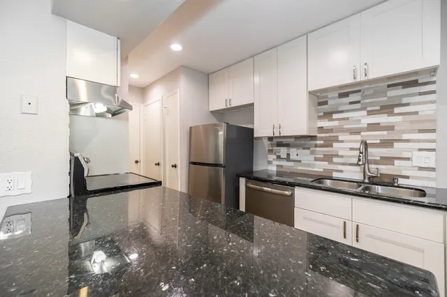a kitchen with stainless steel appliances granite countertop a sink stove and refrigerator