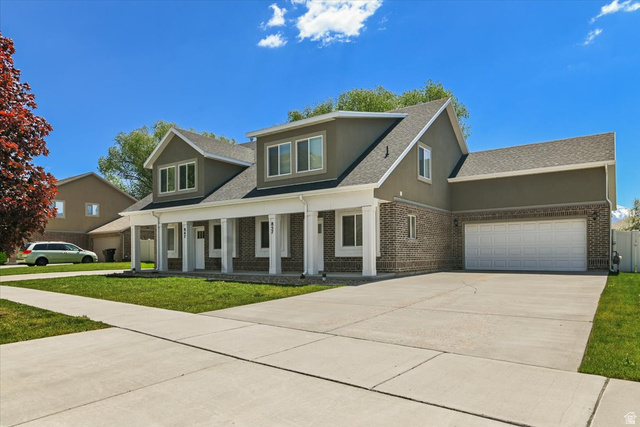 857 225 South Springville, UT 84663 - Photo 21 of 23 Two-story residence featuring a brick and stucco exterior, white columned front porch, multi-pane windows, attached two-car garage, and concrete driveway