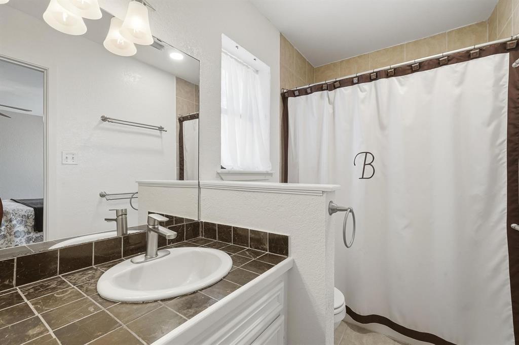 121 Sandy Lane Clyde, TX 79510 - Photo 19 of 30 a bathroom with a granite countertop sink a mirror and a shower