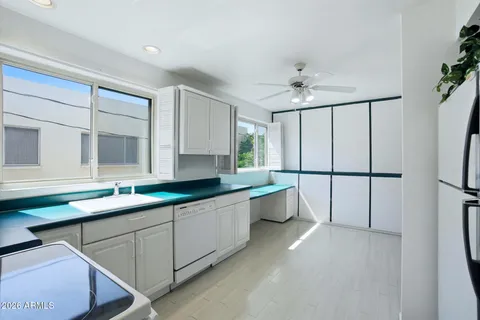 a large white kitchen with a sink a window and stainless steel appliances