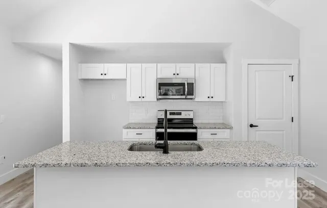 a kitchen with granite countertop a sink a stove and a granite counter tops