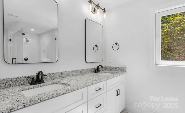 a bathroom with a granite countertop double vanity sink and mirror