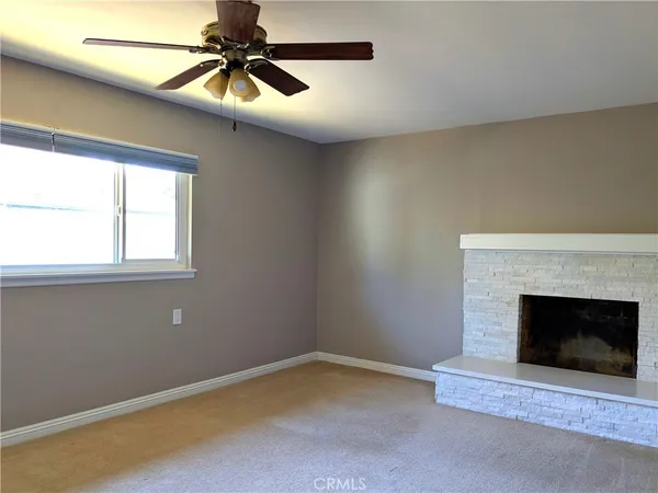 a room with chandelier fan and fireplace