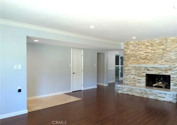 an empty room with wooden floor fireplace and windows