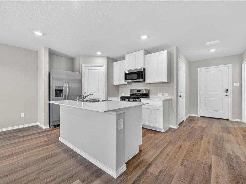 5568 Corduroy Road Krum, TX 76249 - Photo 6 of 23 a kitchen with white cabinets and stainless steel appliances