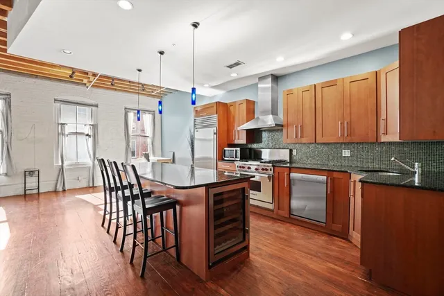 a kitchen with stainless steel appliances granite countertop a table chairs sink and wooden floor