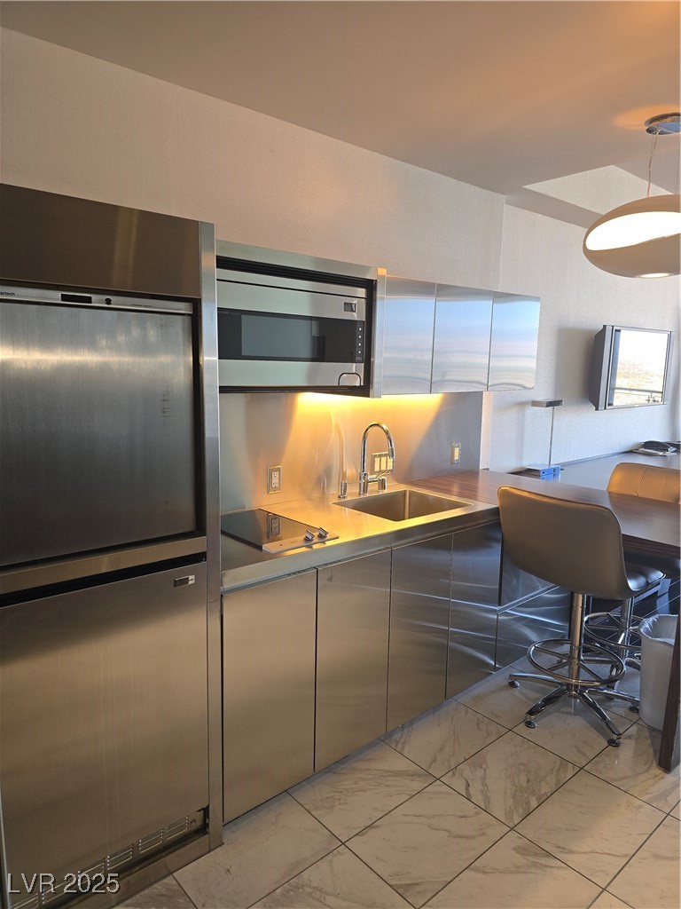 4381 West Flamingo Road, Unit 3109 Las Vegas, NV 89103 - Photo 3 of 28 Kitchen with decorative backsplash, marble finish floor, modern cabinets, a sink, and cooktop