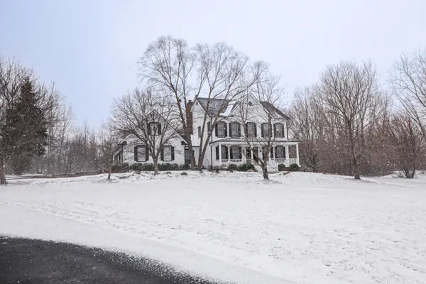 a view of wooden house with a yard covered in snow