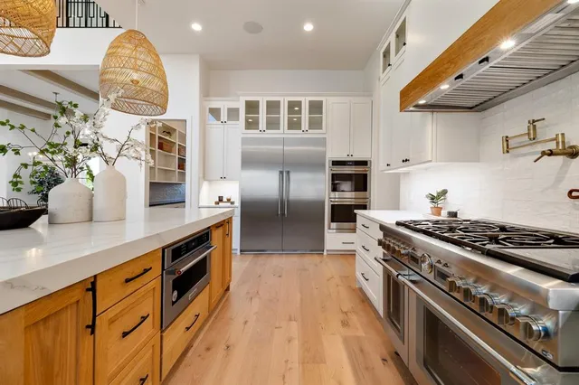 a kitchen with stainless steel appliances granite countertop a lot of cabinets a stove and a wooden floors