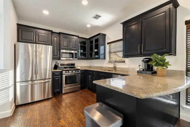 a kitchen with kitchen island granite countertop stainless steel appliances and wooden cabinets