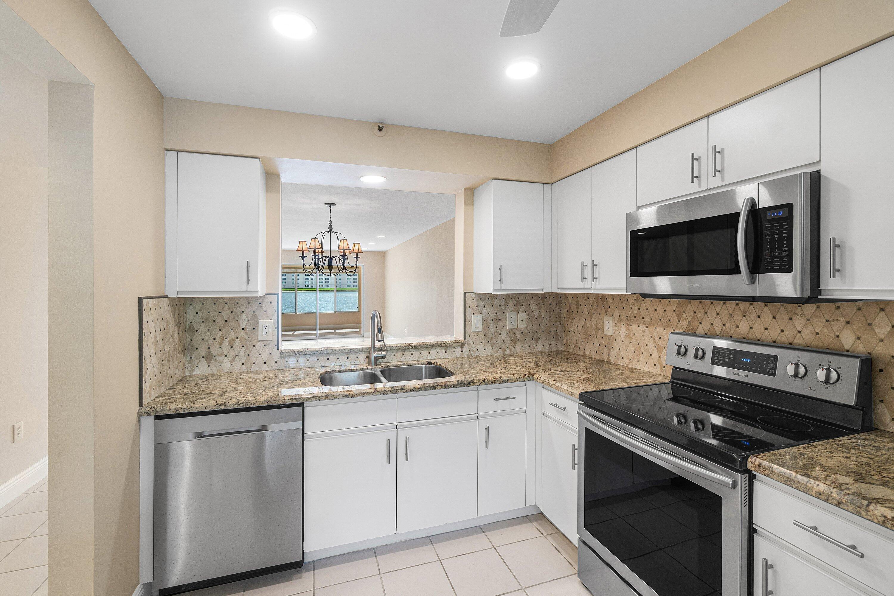 14096 Huntington Pointe Drive, Unit 106 Delray Beach, FL 33484 - Photo 23 of 47 a kitchen with stainless steel appliances granite countertop a stove microwave and sink