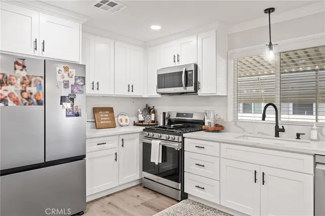 a kitchen with stainless steel appliances granite countertop white cabinets a sink a stove a refrigerator and white cabinets