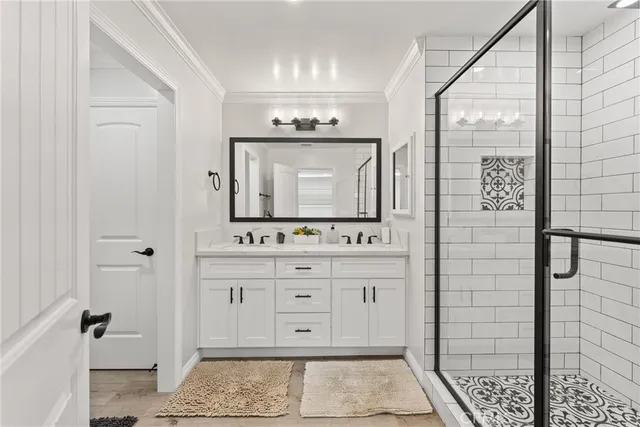 a bathroom with a granite countertop sink a mirror and shower