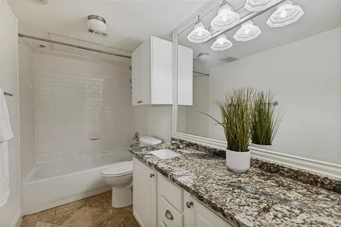 a bathroom with a granite countertop sink a toilet and bathtub