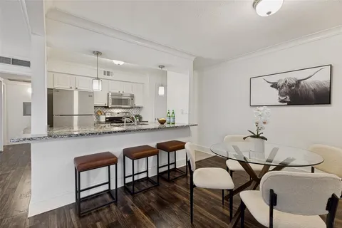 a kitchen with stainless steel appliances kitchen island granite countertop a dining table chairs and a refrigerator