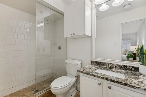 a bathroom with a granite countertop toilet a sink and a mirror
