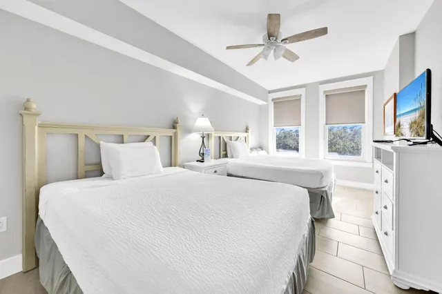 a bedroom with a large bed a flat tv screen and a ceiling fan