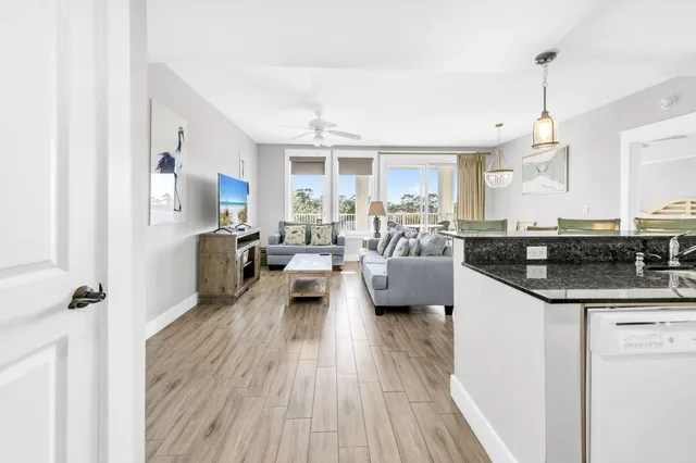 a living room with granite countertop kitchen island stainless steel appliances sink and cabinets