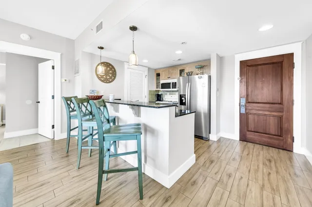 a kitchen with granite countertop a table chairs refrigerator and wooden floor