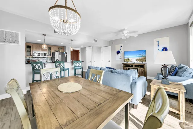 a kitchen with stainless steel appliances granite countertop a stove a refrigerator a microwave oven a dining table and chairs with wooden floor