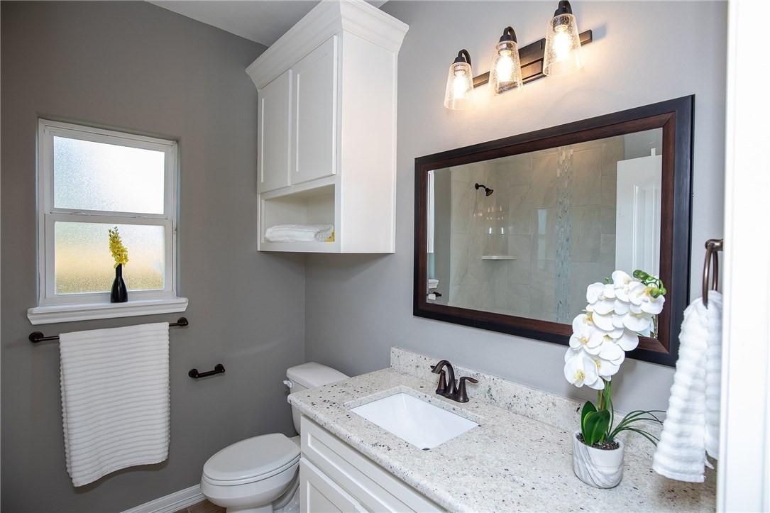 3049 St Eustatius Corpus Christi, TX 78418 - Photo 6 of 8 a bathroom with a granite countertop toilet sink and mirror