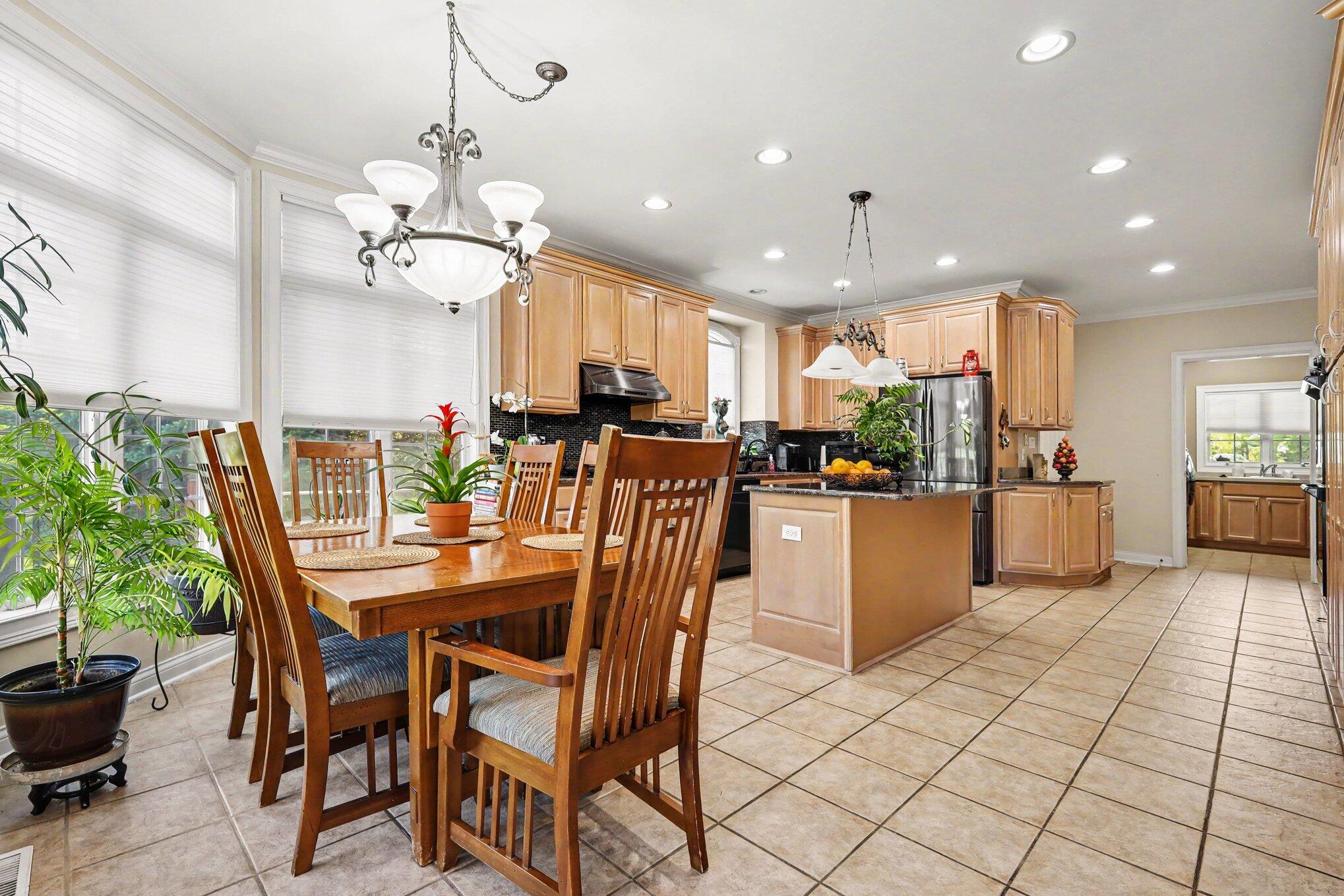 10195 Floyd Street Crown Point, IN 46307 - Photo 4 of 20 a dining room with stainless steel appliances kitchen island granite countertop a table chairs and a refrigerator