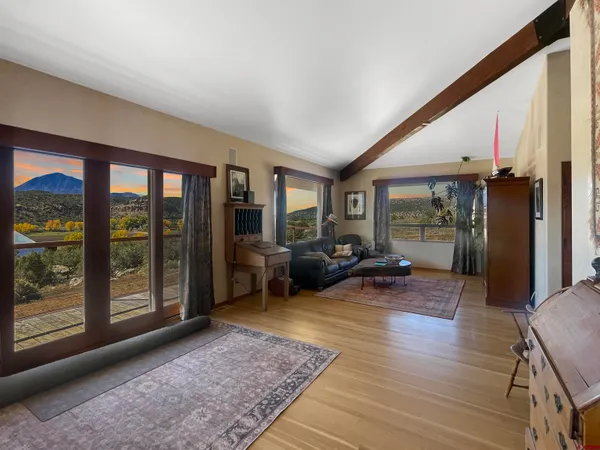 a living room with furniture floor to ceiling window and wooden floor
