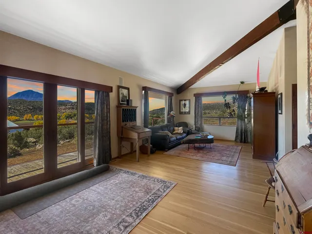 a living room with furniture floor to ceiling window and wooden floor