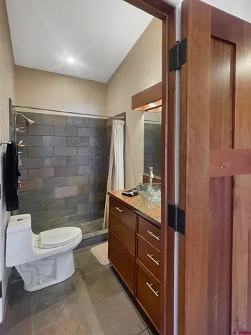 a bathroom with a granite countertop sink a toilet a mirror and shower