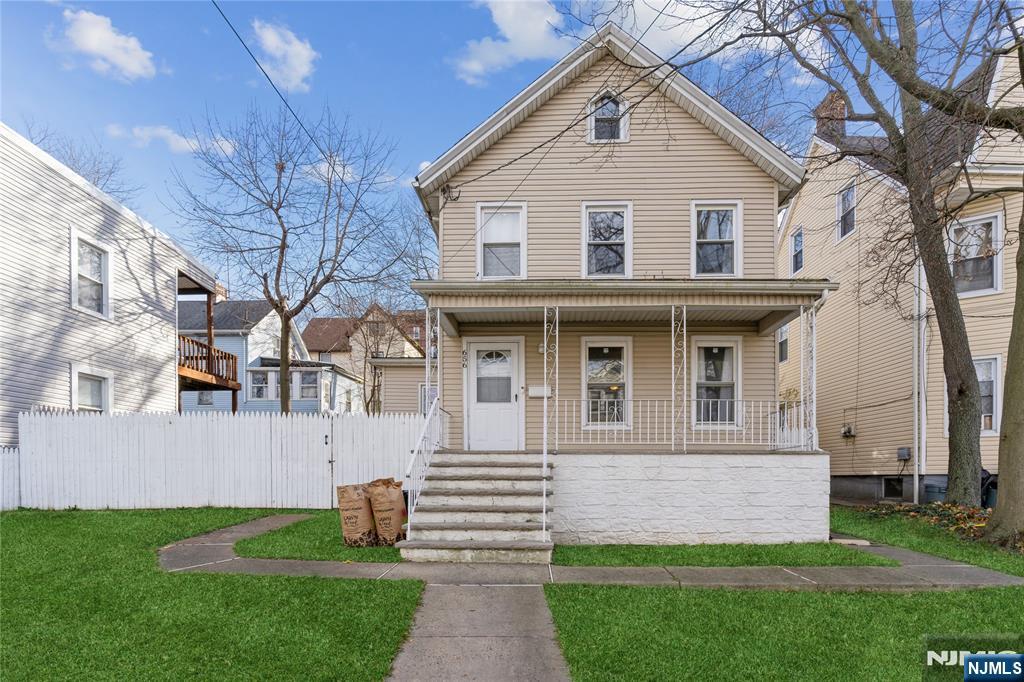 a front view of a house with a yard and an tree