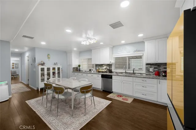 a kitchen with a dining table chairs stove refrigerator and cabinets